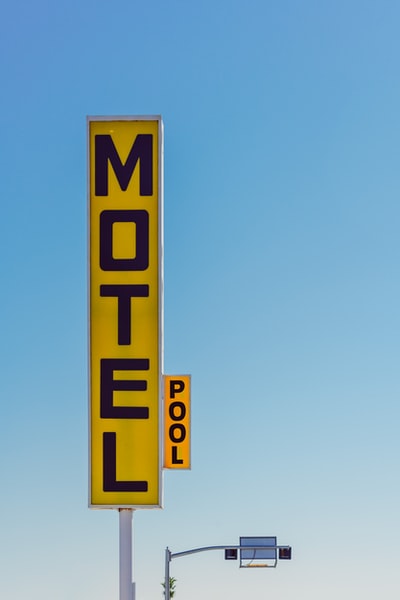 白天拍摄的黄色和黑色汽车旅馆标识